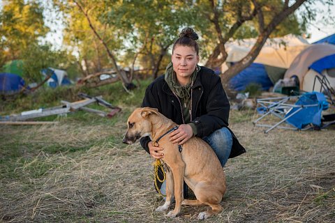 Adriana Furlong, 21, is a member of the Alaskan Aleut Tribe. She lives in Seattle, Wash. and traveled to the Oceti Sakowin camp near Cannon Ball, N.D. to join the #NoDAPL protests. Here, Furlong sits with a dog she calls "Mama" or "MaeMae," who she found in the camp. She's searching for the dog's owners. September 25, 2016.