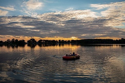 Two young boys play in a raft on Fairy Lake in Stearns County, Minnesota, at sunset.